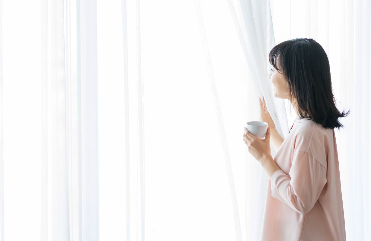 窓越しに日光を浴びる女性
