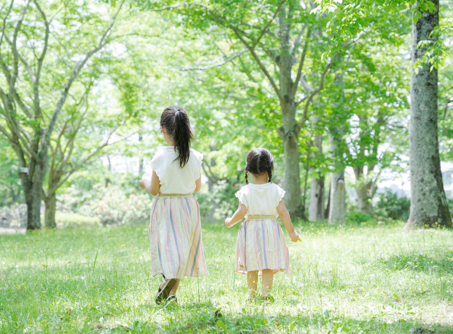 緑に囲まれて散歩する２人の子供